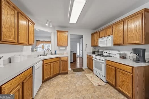 kitchen featuring brown cabinets, white appliances, and light countertops