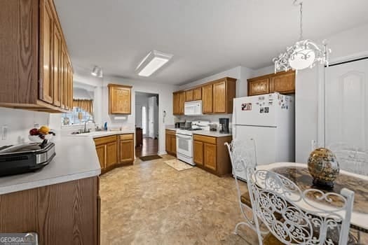 kitchen featuring brown cabinets, white appliances, pendant lighting, and light countertops