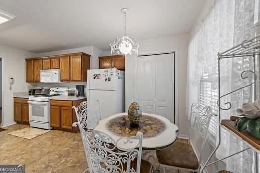 kitchen with white appliances, a chandelier, light countertops, and brown cabinetry