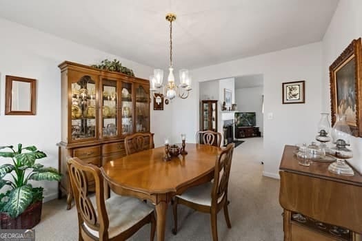 dining space with a chandelier, a fireplace, and carpet floors