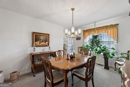 carpeted dining area featuring baseboards and a notable chandelier