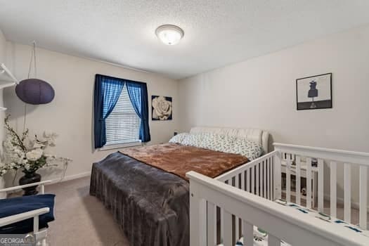 bedroom featuring a textured ceiling, carpet floors, and baseboards