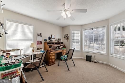 office featuring ceiling fan, a textured ceiling, a wealth of natural light, and light colored carpet