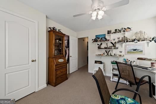 dining room featuring a ceiling fan, light colored carpet, and baseboards