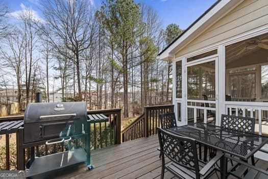 wooden deck featuring a sunroom, a grill, and outdoor dining area