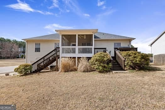 rear view of property with a deck, stairway, and a sunroom