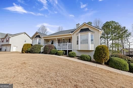 view of front of property featuring a front yard, covered porch, and a chimney