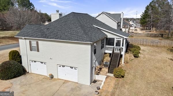 view of side of home with a garage, fence, stairs, driveway, and a chimney