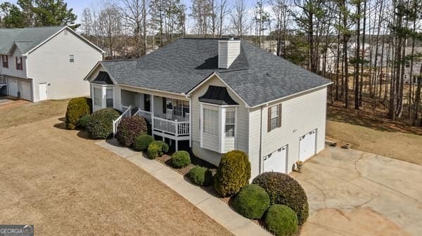 view of front of property featuring covered porch, concrete driveway, a chimney, and an attached garage