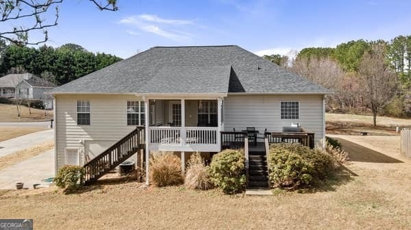 back of house with driveway, a wooden deck, and stairs