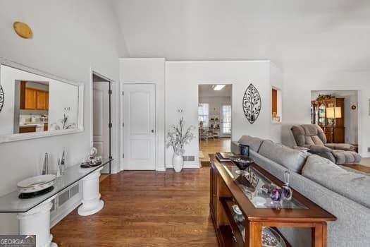 living area featuring visible vents, high vaulted ceiling, and dark wood finished floors