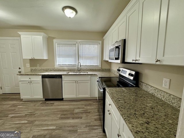 2228 Headland Dr, East Point, GA 30344 - kitchen featuring appliances with stainless steel finishes, light stone counters, light wood-type flooring, and white cabinetry