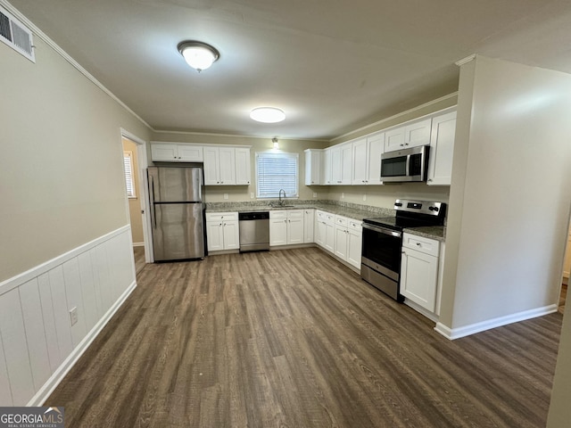 2430 Fern Valley Ct, East Point, GA 30344 - kitchen with appliances with stainless steel finishes, dark wood-style flooring, white cabinets, ornamental molding, and wainscoting