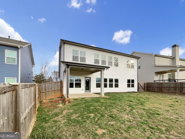 rear view of house with a patio, a lawn, and a fenced backyard