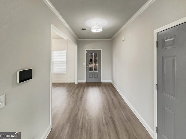 foyer with baseboards, wood finished floors, visible vents, and crown molding