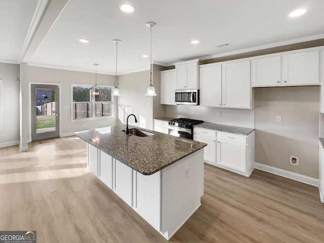 kitchen with appliances with stainless steel finishes, light wood-style floors, a sink, and ornamental molding