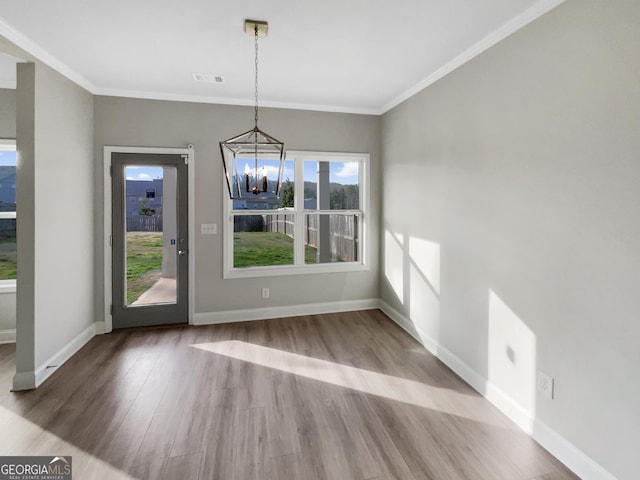 unfurnished dining area with wood finished floors, visible vents, baseboards, ornamental molding, and an inviting chandelier