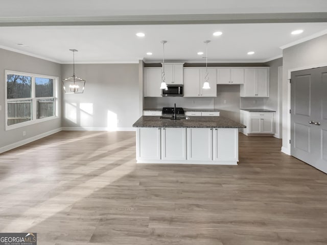 kitchen with baseboards, stainless steel microwave, light wood-style floors, white cabinetry, and a sink