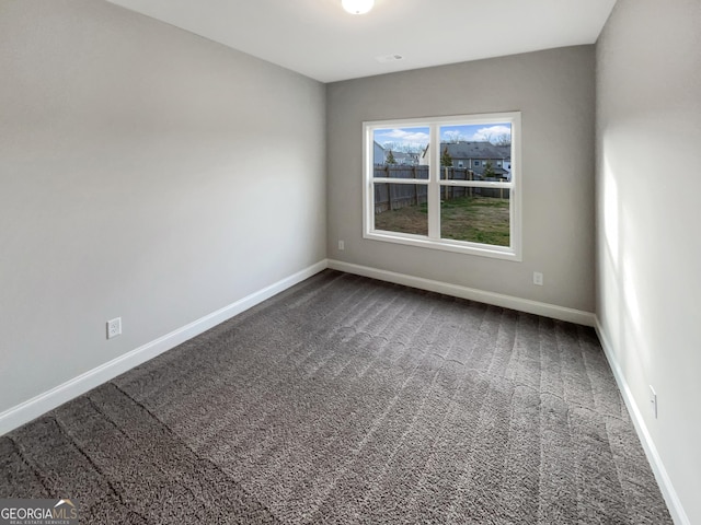 unfurnished room with dark carpet and baseboards