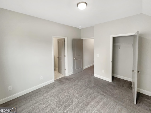 unfurnished bedroom with carpet, baseboards, vaulted ceiling, and a closet