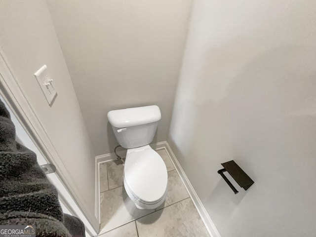 bathroom with toilet, baseboards, and tile patterned floors