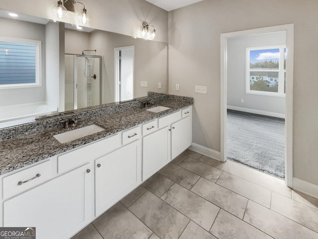 full bath featuring a stall shower, a sink, and baseboards