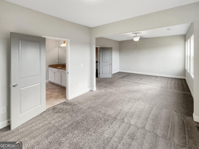 unfurnished bedroom with baseboards, ensuite bathroom, and light colored carpet