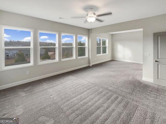 carpeted empty room featuring baseboards, visible vents, and a ceiling fan