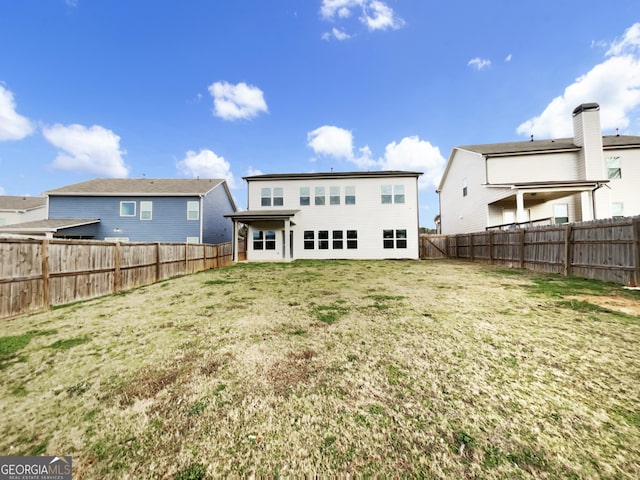 back of property featuring a fenced backyard and a yard