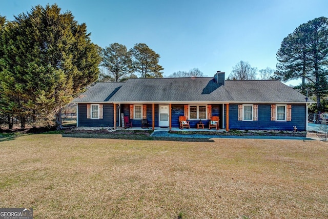 ranch-style house featuring covered porch, roof with shingles, a chimney, and a front yard