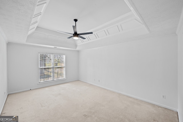 empty room with ceiling fan, baseboards, a raised ceiling, and carpet flooring