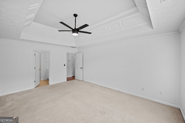 unfurnished bedroom featuring baseboards, ceiling fan, ornamental molding, a tray ceiling, and carpet flooring