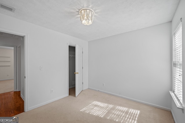 unfurnished bedroom featuring visible vents, a textured ceiling, baseboards, and multiple windows