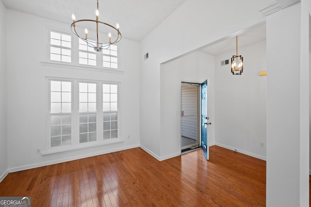 entryway with visible vents, a chandelier, wood-type flooring, and baseboards