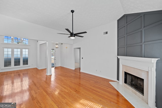 unfurnished living room with a fireplace with flush hearth, visible vents, light wood-style flooring, and a textured ceiling