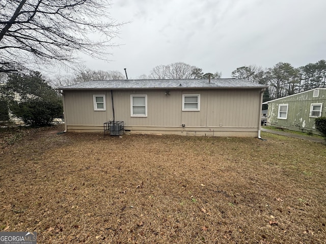 rear view of property featuring crawl space, roof with shingles, and a yard