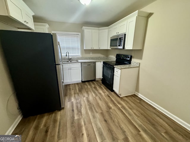 kitchen with stainless steel appliances, a sink, baseboards, white cabinets, and light countertops