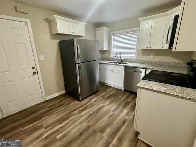 kitchen featuring appliances with stainless steel finishes, dark wood-type flooring, a sink, and white cabinetry