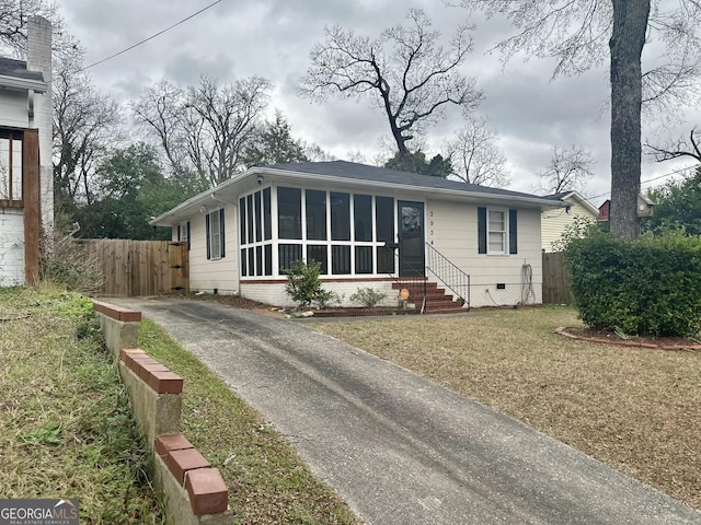 view of front of property featuring aphalt driveway, a sunroom, crawl space, fence, and a front lawn