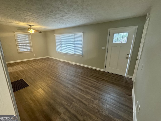 foyer with dark wood-style floors, visible vents, a textured ceiling, and baseboards