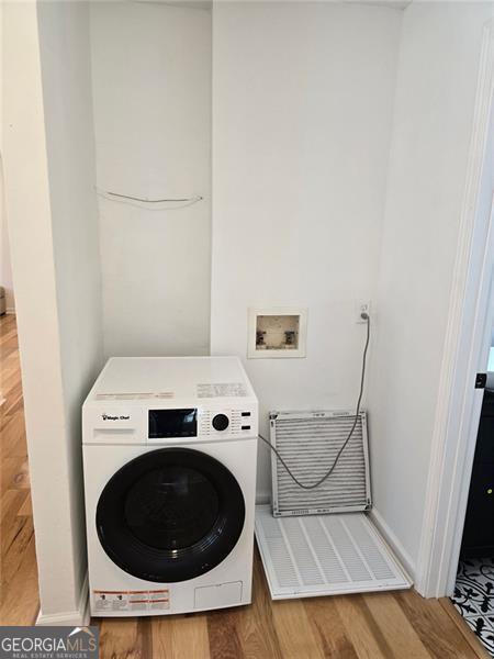 laundry area featuring washer / dryer, laundry area, baseboards, and wood finished floors