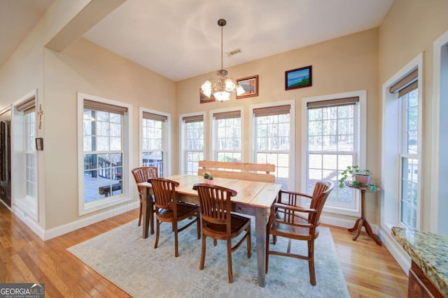 dining room featuring baseboards, visible vents, light wood finished floors, and an inviting chandelier