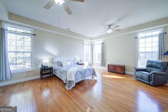 bedroom featuring light wood-style floors, visible vents, baseboards, and a ceiling fan