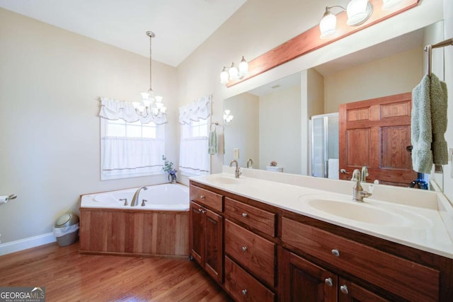 full bathroom with double vanity, wood finished floors, a sink, and an inviting chandelier