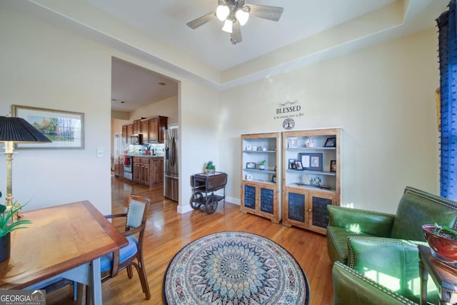 living room featuring light wood-style flooring, baseboards, and a ceiling fan