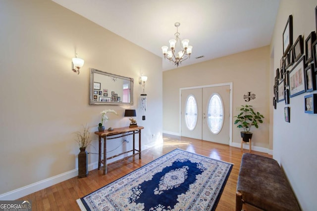 foyer entrance featuring baseboards, an inviting chandelier, and wood finished floors