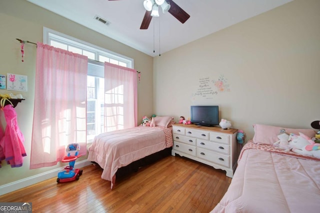 bedroom featuring ceiling fan, hardwood / wood-style flooring, visible vents, and baseboards