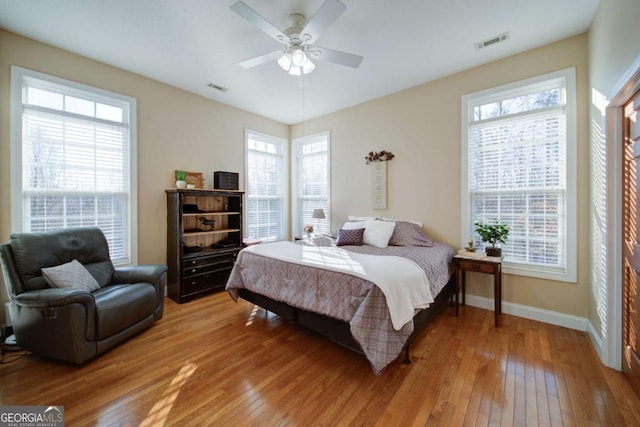 bedroom featuring multiple windows, hardwood / wood-style flooring, and visible vents