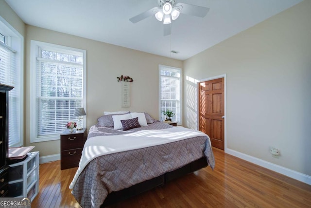 bedroom with multiple windows, baseboards, and wood finished floors