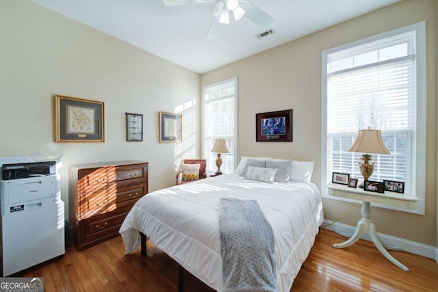 bedroom featuring a ceiling fan, light wood-type flooring, visible vents, and baseboards